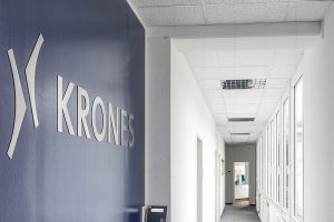 Langer Flur der Firma Krones mit einer blauen Wand mit Firmenlogo. Becker Bernhrad Gewerbeimmobilien Lagenfeld.